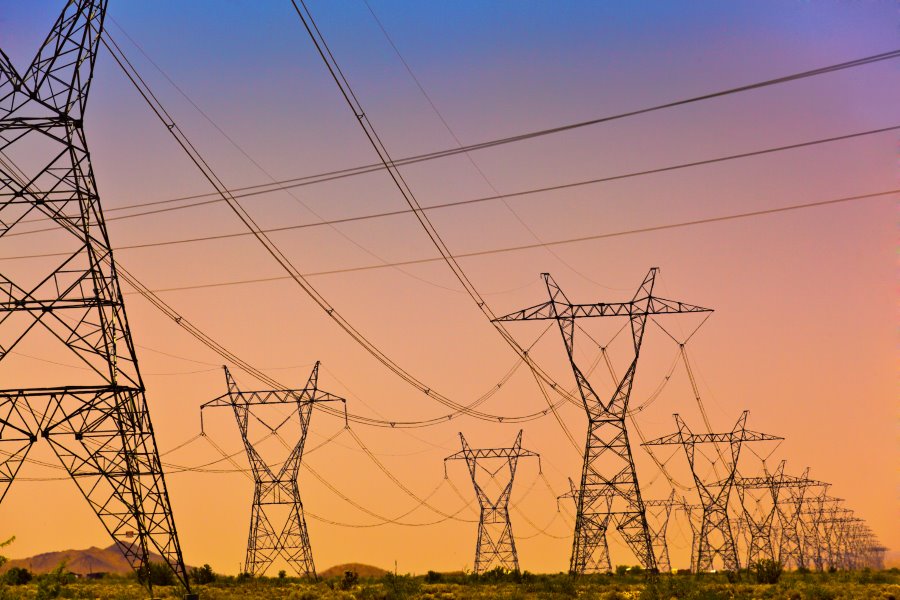 Electric power lines and transmission tower, electric grid at sunset